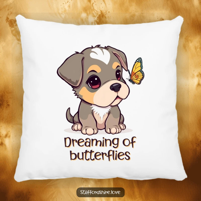 Funny Staffordshire pup with one ear flopped over, looking curiously at a fluttering butterfly on a soft, decorative pillow.