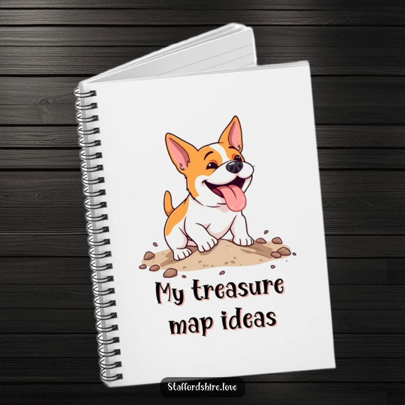 Funny, energetic Staffordshire dog with a happy pant, digging enthusiastically in soft earth on the cover of a lined notebook.