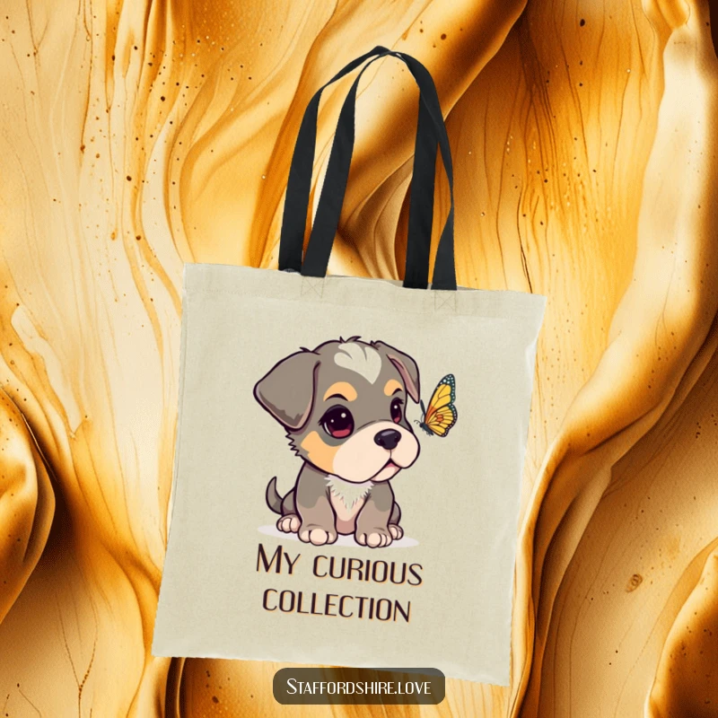 Funny Staffordshire pup with one ear flopped over, looking curiously at a fluttering butterfly on a durable and stylish tote bag.