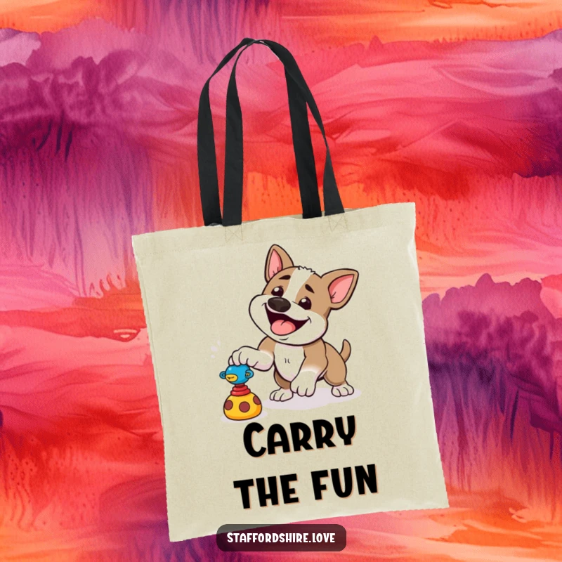 Funny tote bag showing a happy Staffordshire dog playfully pouncing at a toy, perfect for carrying fun items.